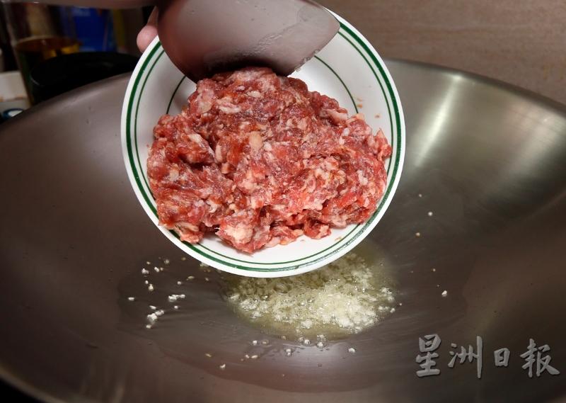 锅里热油后，爆香蒜米。接着将腌制好的猪肉碎倒入锅里，炒至熟及呈焦黄色。
