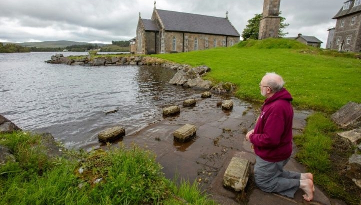 Father Flynn prays barefoot at the penitential beds where pilgrims normally come at Lough Derg. AFP