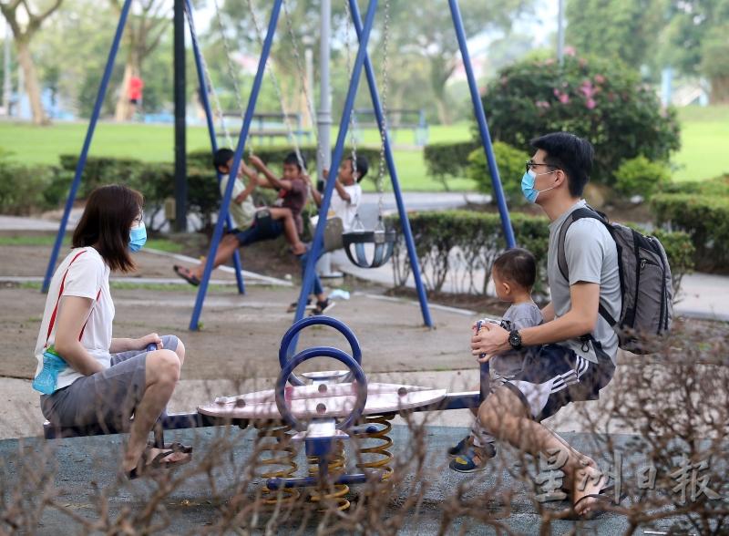 家长带著孩子使用公园游乐设施，也会戴上口罩。 
