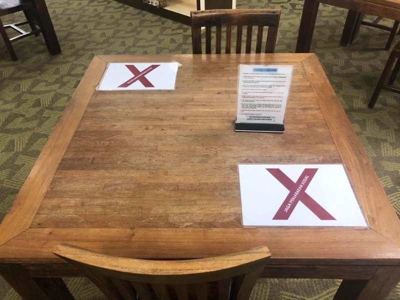 公共图书馆每张桌子粘上人身距离标志。
