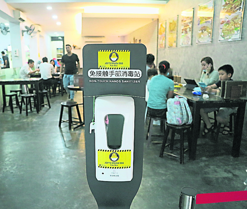 有餐厅业者提供免接触手部消毒站，让顾客通过感应器使用搓手液消毒。