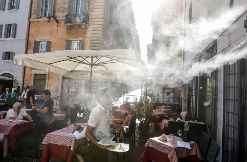 图为在意大利首都罗马市中心一家咖啡馆外，风扇喷出水雾，为顾客降温解暑。（美联社照片）