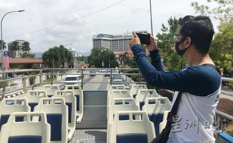 怡保人华利迪在HOHO 巴士上，以手机捕捉怡保街道的风情。


