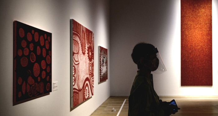 A visitor wearing a face shield stands near to A visitor wearing a face shield stands near to