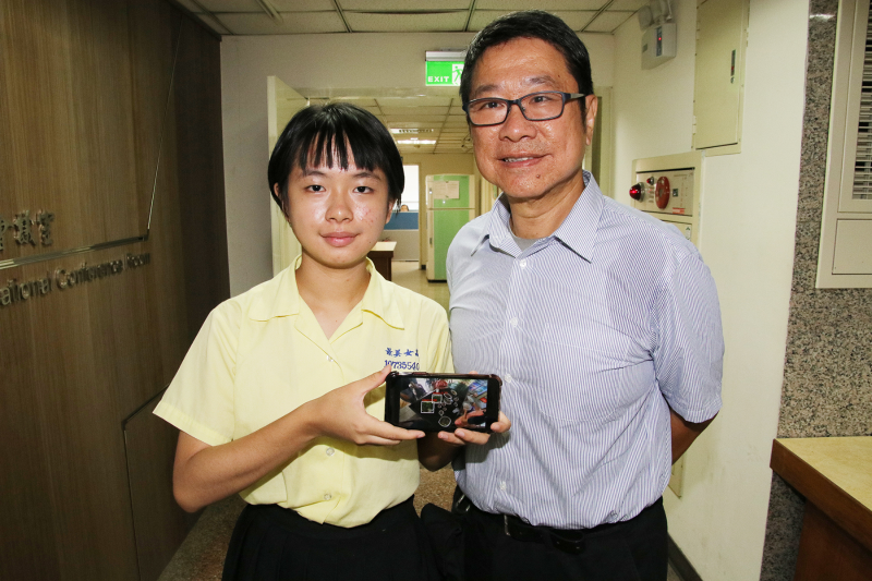 陈翎（左）使用YOLO软体辨识马来西亚传统菜肴，父亲从旁指导协助。（台湾内政部移民署台北站提供)