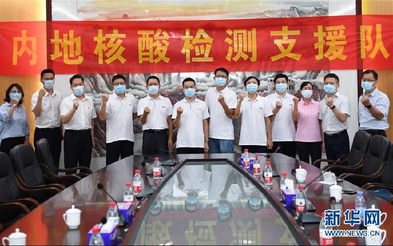 来自广东省各医院的内地核酸检测支援队的7名先遣队队员在深圳湾口岸出发前和送行人员合影。  （新华社）