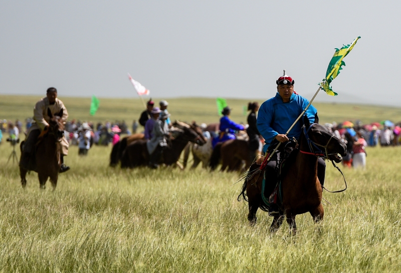 牧民们骑马参加那达慕大会。  
