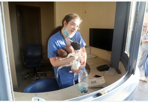一名护士在受损的医院内照料3名婴儿。