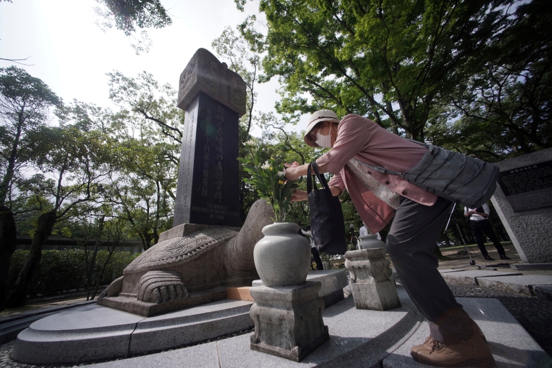 一名女子在广岛和平纪念公园的韩国受害者纪念碑前献花并祈祷。