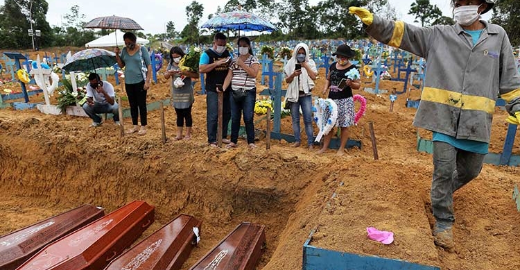Mourners stand besides a mass grave in Manaus amidst the coronavirus pandemic. AFP