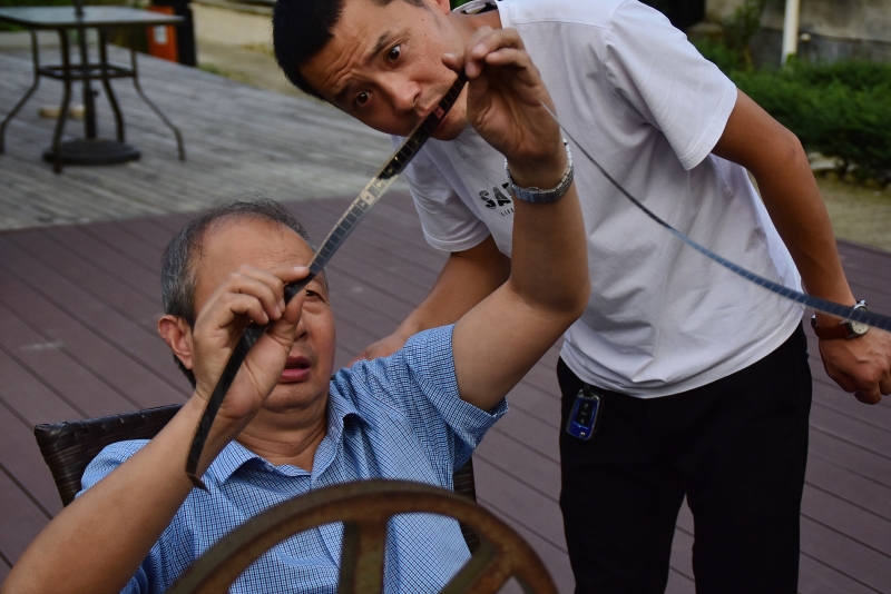 朱生荣（左）和儿子朱强在电影开映前检查胶片位置。（图：新华社）  