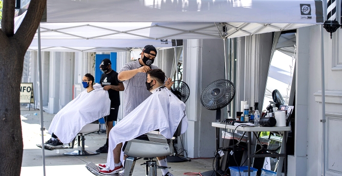 Grey Matter LA stylists wearing face masks cut the hair of clients at a distance on the sidewalk amidst the coronavirus pandemic in Los Angeles, California. AFP