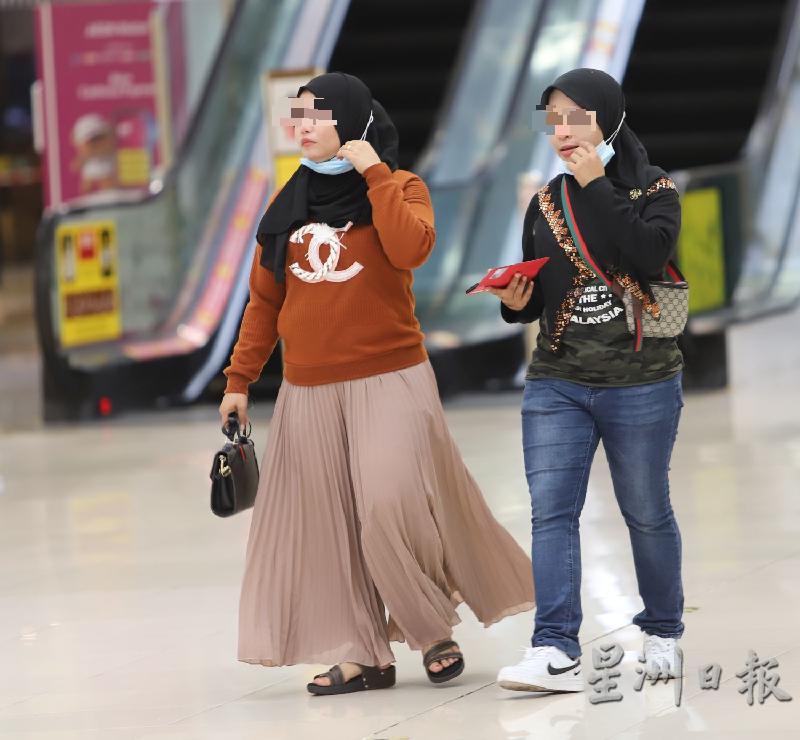 两名女性在购物广场为了拍摄效果，暂时将口罩拉下。