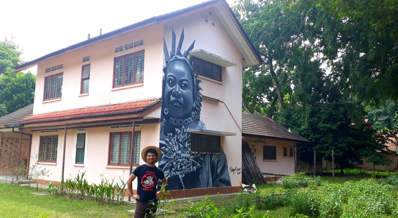 沙果耀与他的大型壁画，画中是来自雪兰莪州加厘岛（Carey Island）的玛美里族原住民。（图：受访者提供）