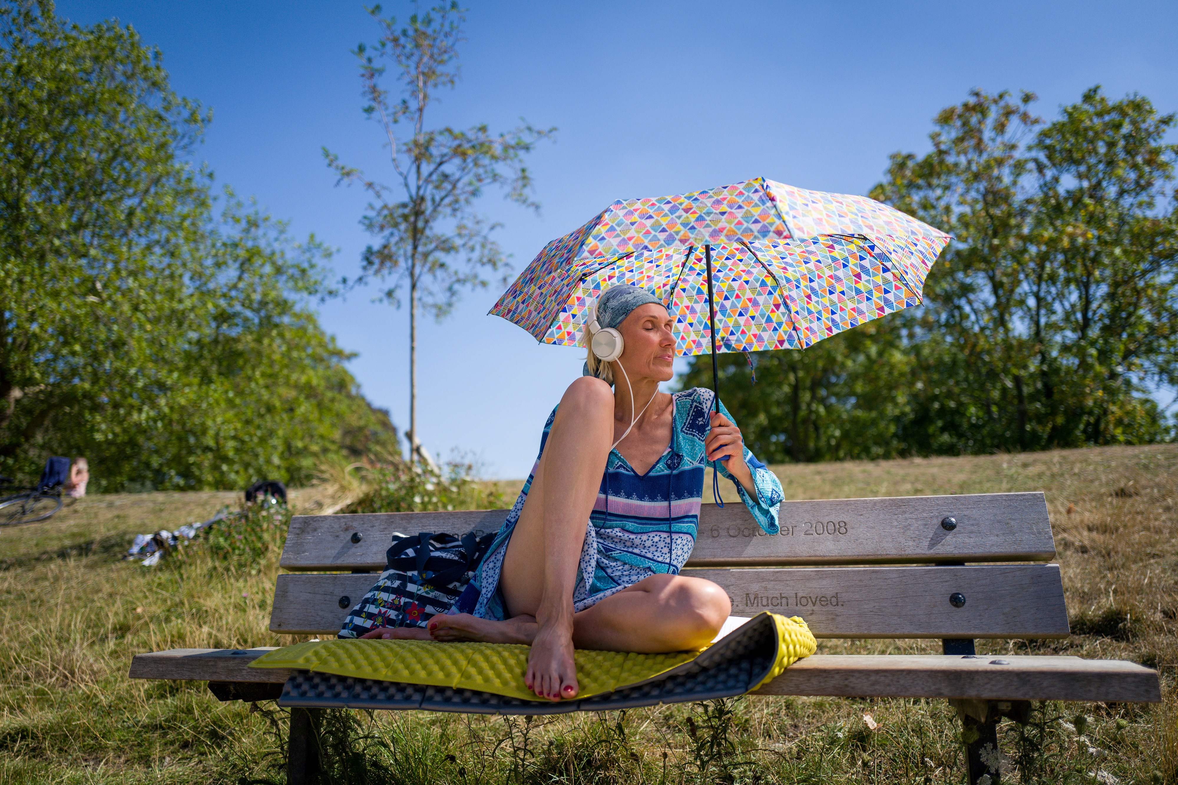 尽管高温笼罩，乐在其中的也大有人在。伦敦市郊一名女子撑著阳伞，享受着阳光。 (法新社图片)