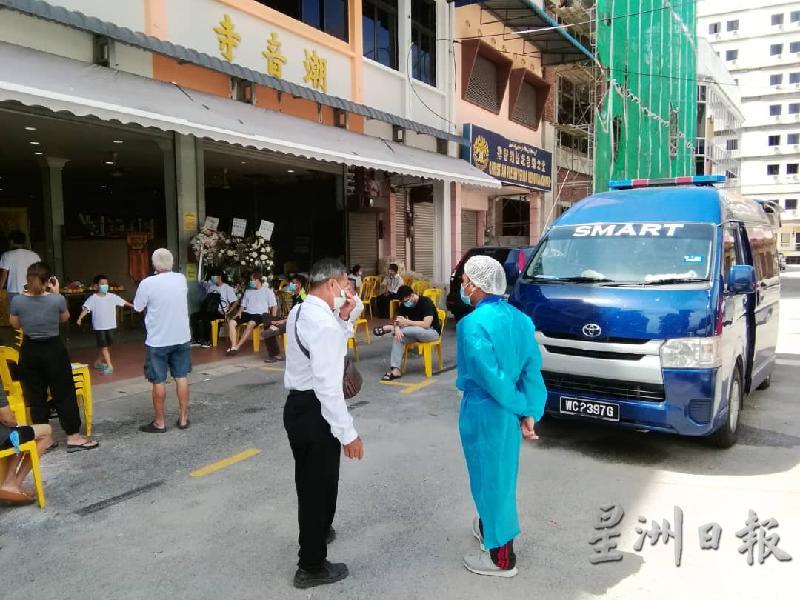 救护车和医护人员在殡仪馆外准备将吴佩玉载去隔离中心。