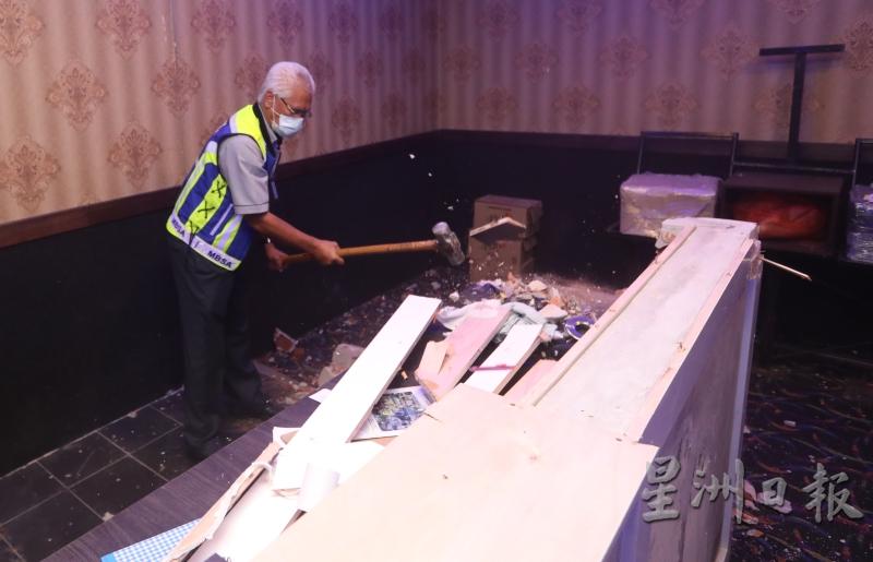 市议会官员用铁锤拆除违规商店的设备。
