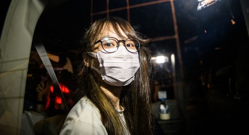 Agnes Chow looks out of a car window while being driven away by police from her home. AFP