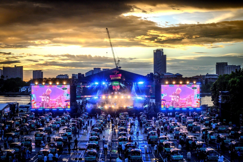 火红的晚霞与舞台上投射出的五彩灯光，将河畔夜市空地上整齐排列的200辆“嘟嘟车”镀上炫彩。
