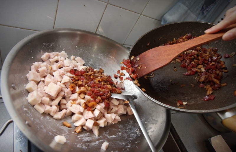 炒熟芋头，快熟时加点水炒一炒，接着倒入已炒好的虾米、小红葱、冬菇及腊肠。