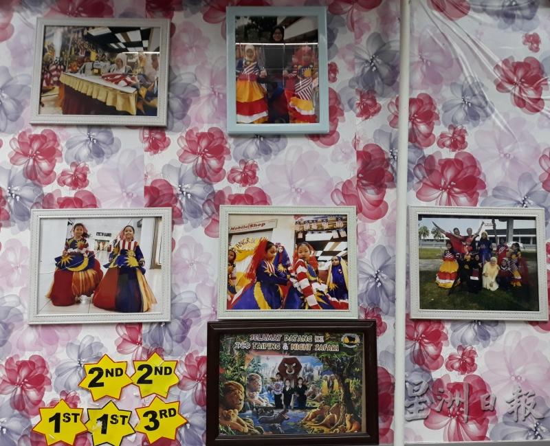 裁缝店内的墙壁上，挂了多张玛哈妮孪生女儿穿上国旗服装的照片和她们的“奖牌”。