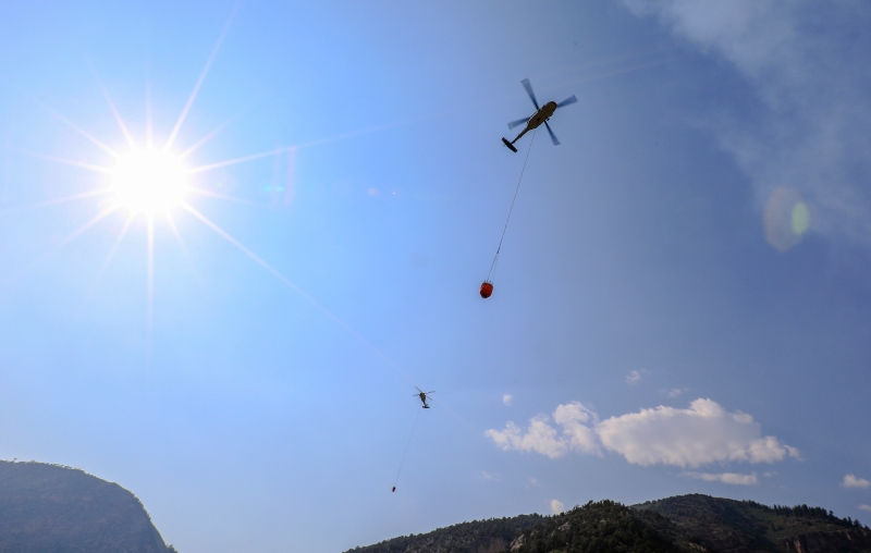 直升机从最近的水源吸水到火源地区洒水灭火。（美联社照片）