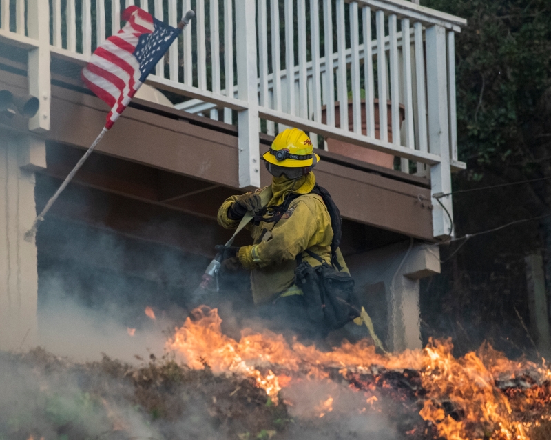 一名消防员尽力的在扑灭火势以抢救居民的家园。（美联社照片）)