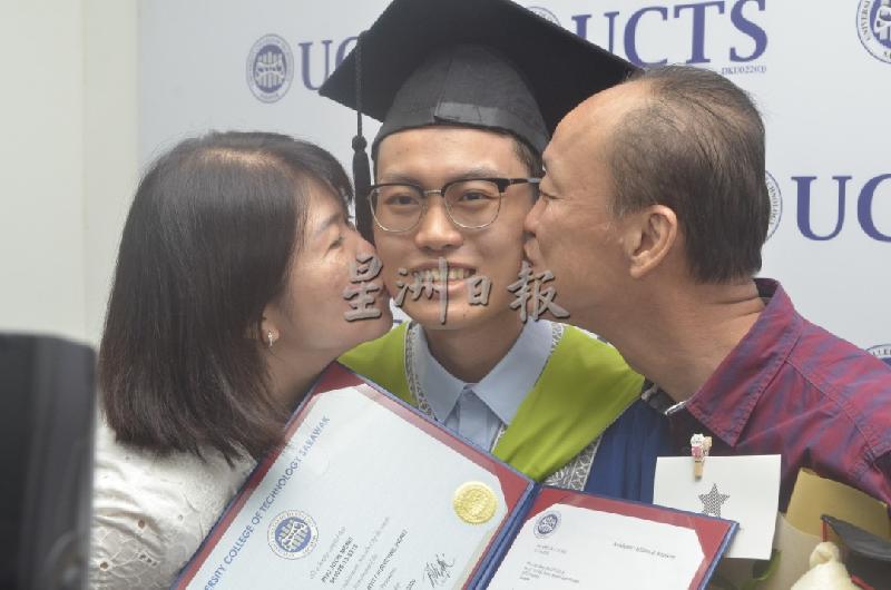 “孩子，我们以你为荣！”潘润明（中）获颁工料测量因病免试学士学位，其父母亲吻他的脸颊。