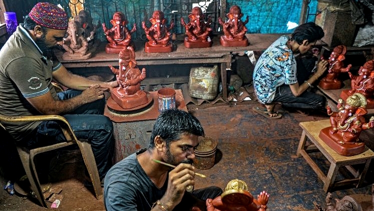 Yusuf Zakaria Galwani (L) and his staff work on Ganesha idols at his workshop inside the Dharavi slum in Mumbai. AFP