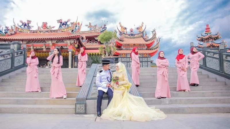 年轻巫裔新人穿着端庄又华丽的礼服，在华人庙宇前拍摄婚照。（西天宫提供）
