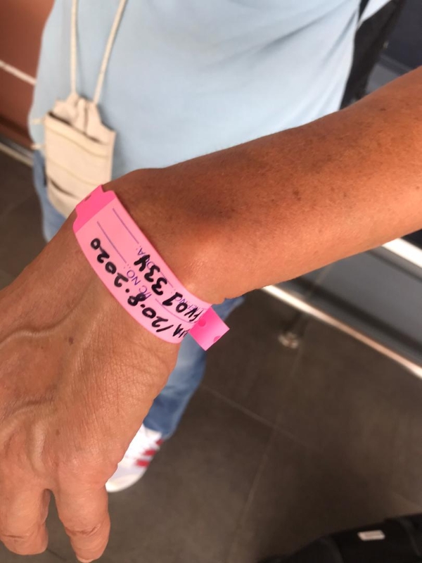 男子戴粉红色隔离手环，上面写著8月20日。