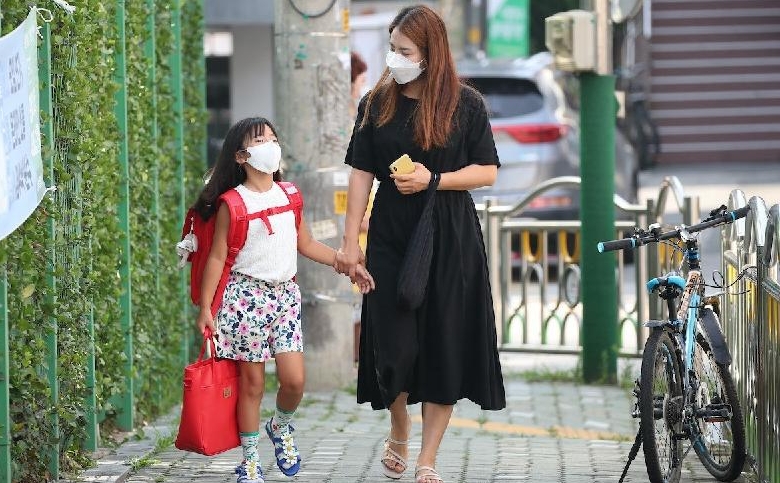 A mother and her daughter on their way to an elementary school in Seoul. AFP