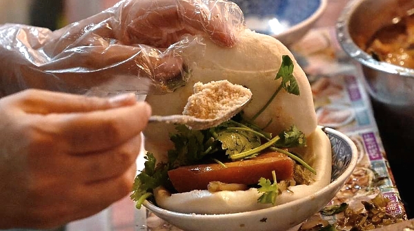 An employee prepares a gua-bao, or pork belly bun, at the Huaxi Night Market in Taipei. AFP
