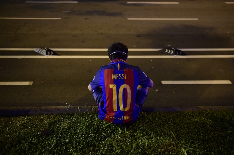 梅西渴望离开巴塞罗那，下一站可能是曼市，图为一名伤心的巴塞球迷穿着梅西的球衣坐在诺坎普球场外。（法新社照片）