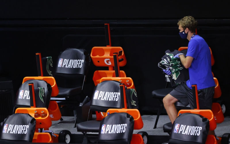 NBA球员决定继续参加季后赛，图为昨日公鹿队决定抵制比赛后，一名职员从空荡荡的凳子上收回毛巾。（法新社照片）