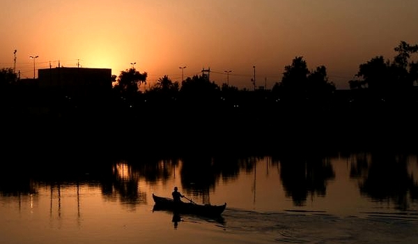 A fisherman rows his boat along the Euphrates river at sunrise. AFP