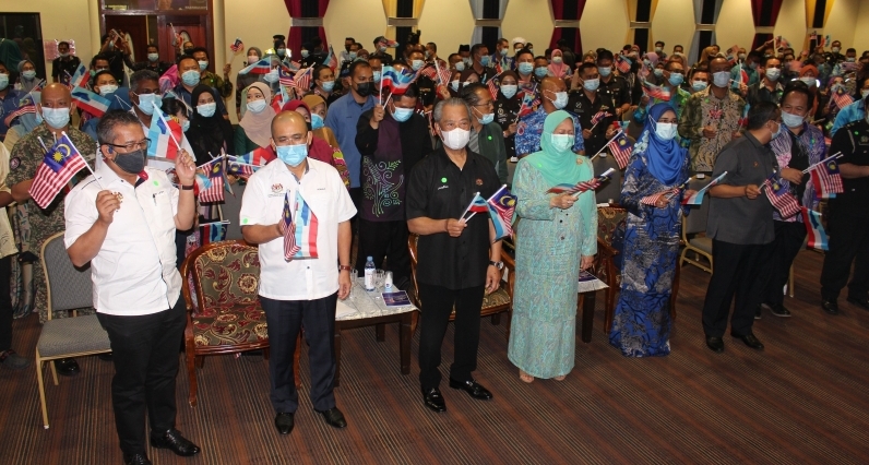 慕尤丁（左三）与众来宾及公务员挥动手中的国州旗。