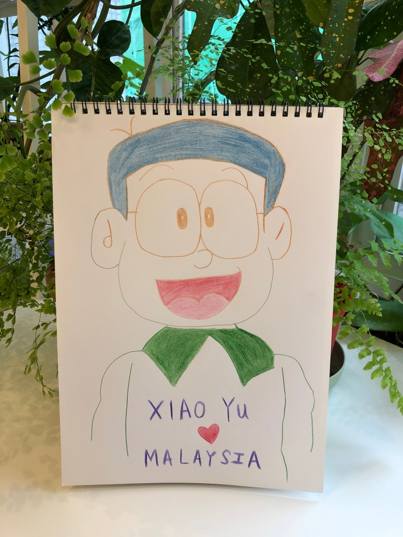 小玉每一次都会把自己形容成“笨大雄”，所以她画上“自己”，用很直接、纯粹的方式，高喊：“我爱马来西亚。”
