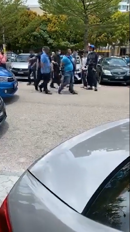 警方将蓝衣抢匪带走。
