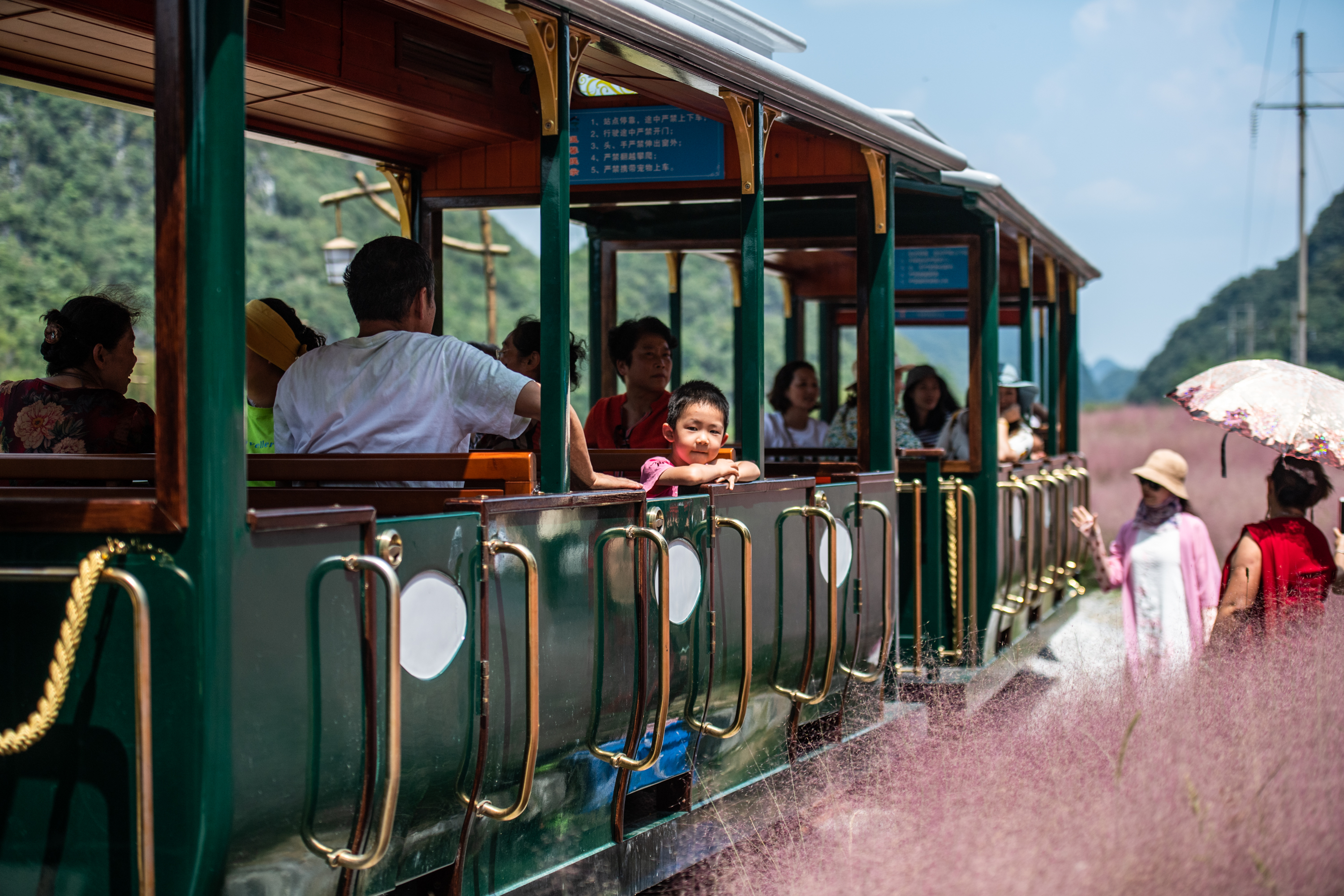游客在长顺县神泉谷景区内乘坐观光小火车游览。　
