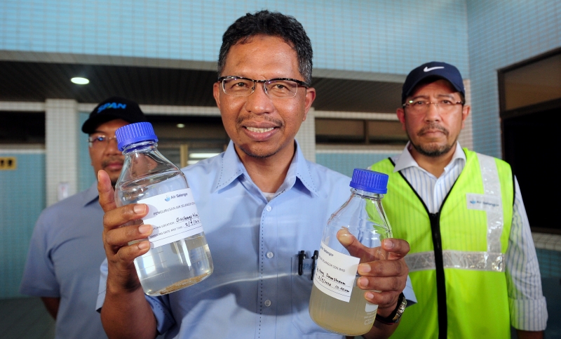 环境与水务部秘书长拿督斯里再尼（中）周五早上巡视雪兰莪河第一期滤水站时，展示当局抽取的水源样本。