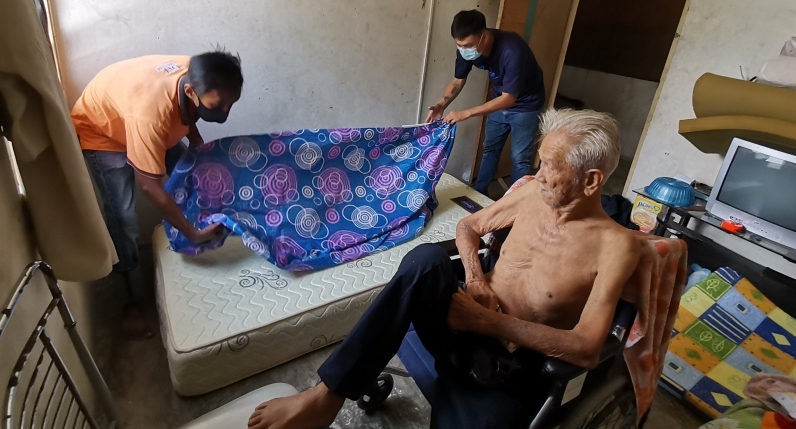 Furniture shop workers put on the new bedsheet for Ye, who is on wheelchair. SIN CHEW DAILY