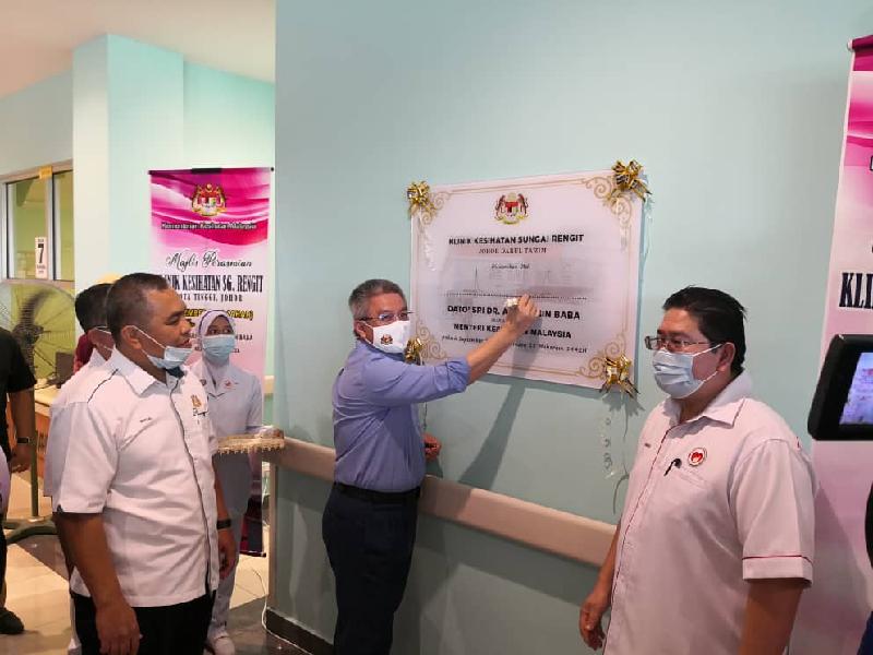 阿汉峇峇（中）在边佳兰四湾政府诊所开幕纪念匾上签署留字。