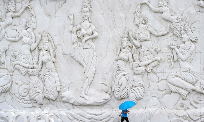 An employee holding an umbrella while walking in front of a wall made of white sand imitating ice in the "Frost Magical Ice of Siam" park outside Pattaya, Thailand. AFP An employee holding an umbrella while walking in front of a wall made of white sand imitating ice in the "Frost Magical Ice of Siam" park outside Pattaya, Thailand. AFP