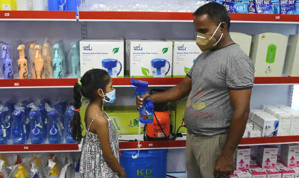 A storekeeper shows a child a fan-sprinkler used for spraying disinfectant at a shop in Vallabh Vidyanagar. AFP