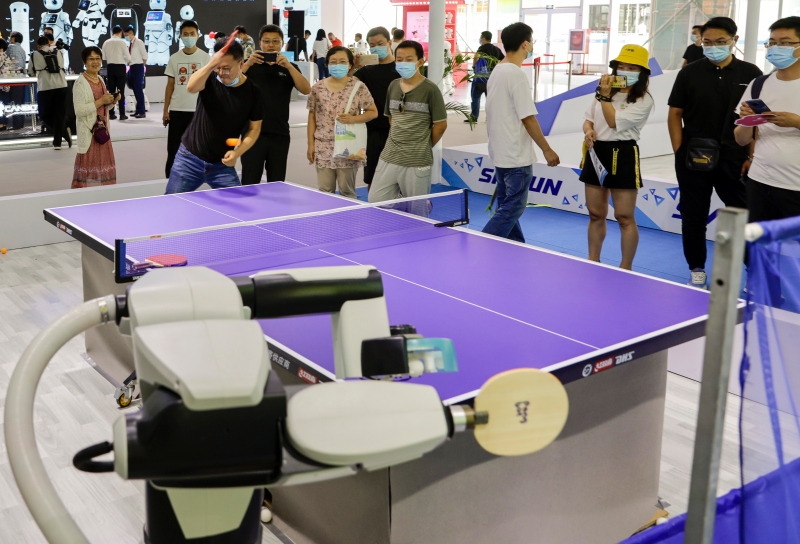 参观者现场挑战乒乓发球机器人。

