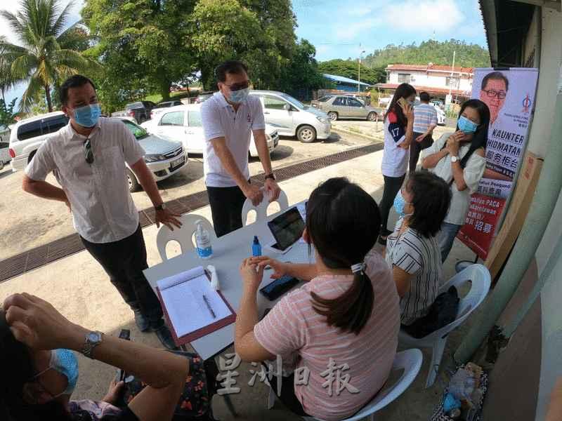 潘明丰（站者左二）到设在华美园巴刹的选民流动服务柜台视察。