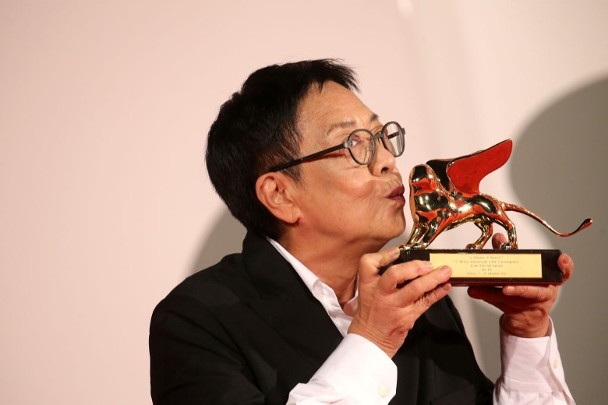 许鞍华是首名华人女导演获终身成就金狮奖，开心亲吻奖座。
