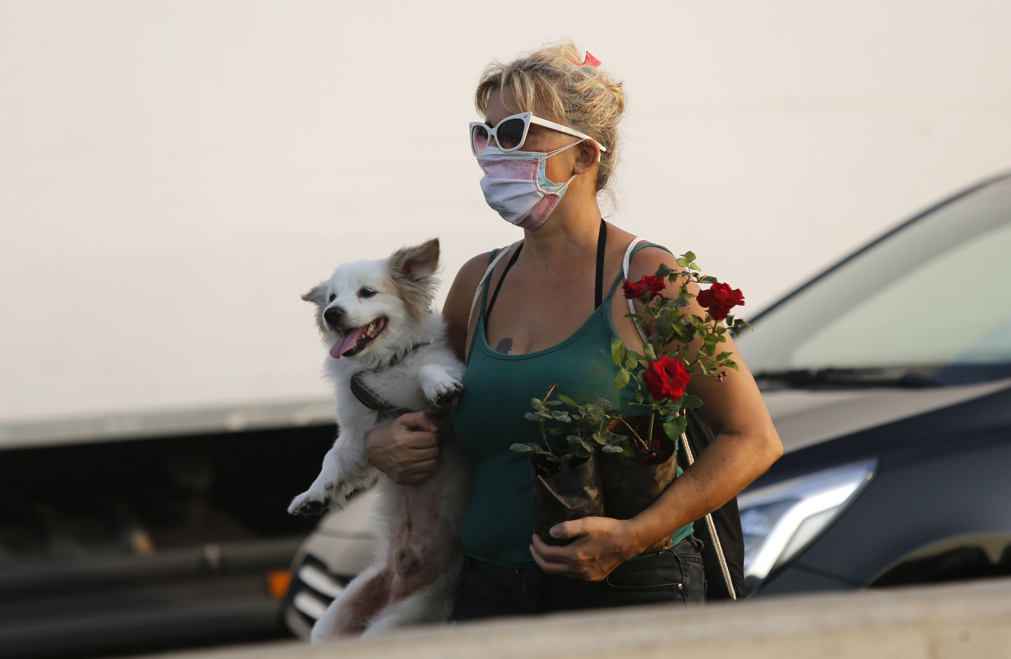 一名女子带著狗和鲜花参加悼念活动。（图：新华社）