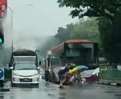 男子冒雨推着坐在轮椅上的年长人士过马路。（图截自脸书视频）